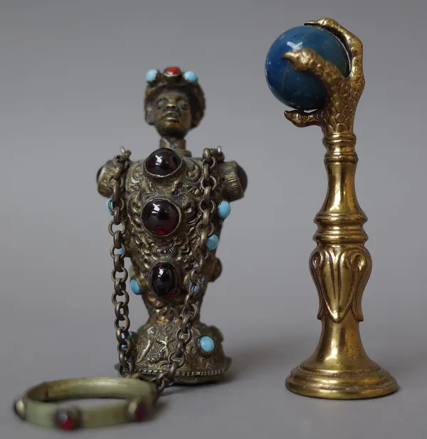 A gilt metal figural scent bottle, early 20th century, modelled as a Nubian male with inset turquoise and red stones over a plain matrix seal with rin