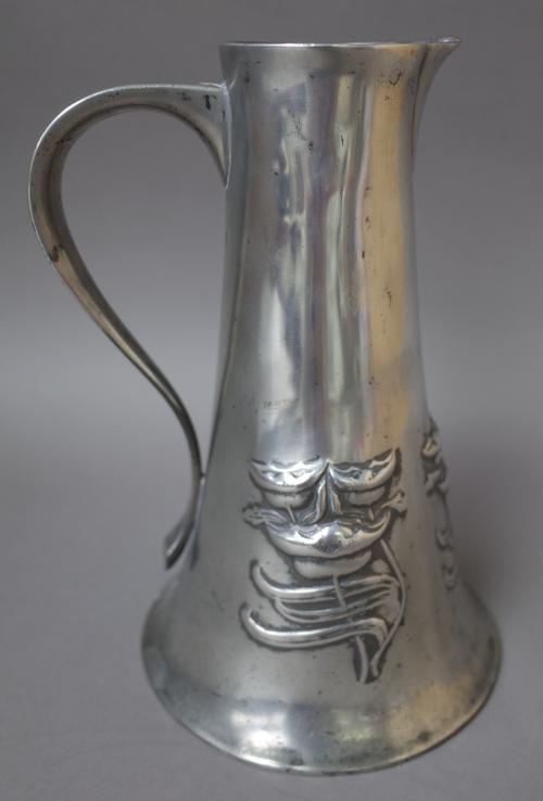 A Liberty Tudric pewter water jug, after a design by Archibald Knox, decorated with relief stylised flowers against a tapering circular body, no. 028,