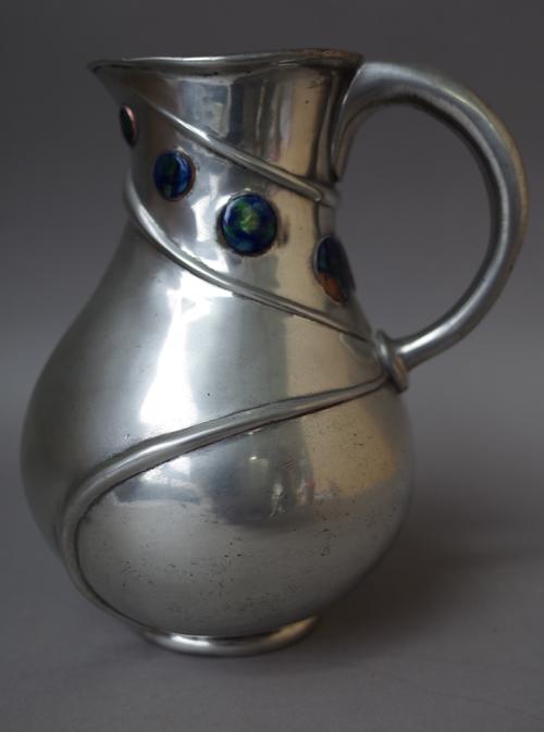 A Liberty Tudric pewter jug, after a design by Archibald Knox, with enamelled roundels to the bulbous body, no. 052, stamped marks, 18.5cm high.