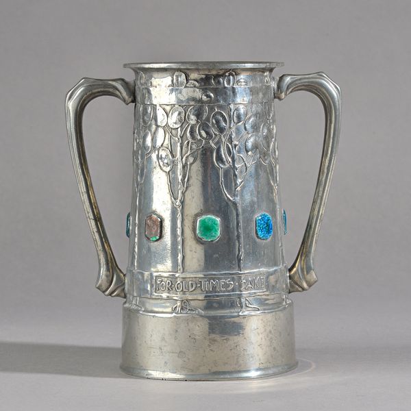 A Liberty Tudric pewter two handled pewter loving cup by David Veazey, the body cast with stylised trees and enamelled roundels, titled 'FOR OLD TIMES