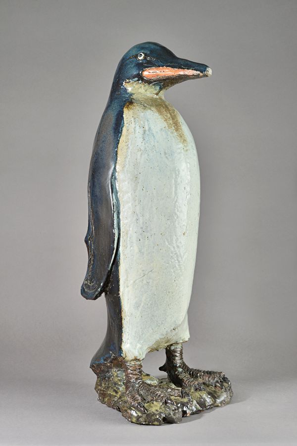 In the manner of Tracey Elizabeth Wright, a saltglaze stoneware penguin, unsigned, on a naturalistic shaped base,(a.f.) 71cm high. Illustrated.