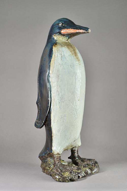 In the manner of Tracey Elizabeth Wright, a saltglaze stoneware penguin, unsigned, on a naturalistic shaped base,(a.f.) 71cm high. Illustrated.