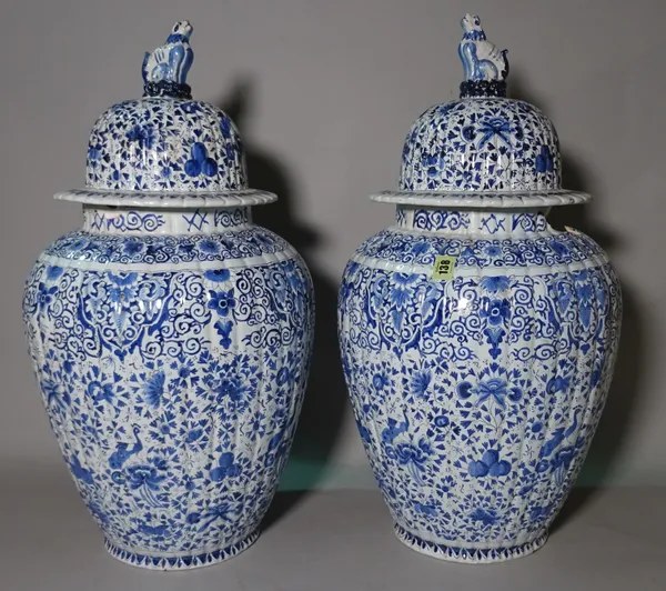 A pair of 19th/20th century Dutch Delft blue and white ribbed ovoid vases and covers, peacocks amongst flowers, 64cm high. (a.f.).