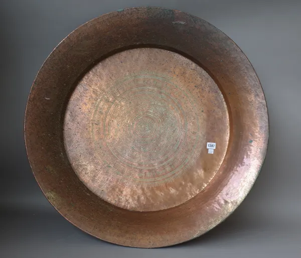 A large copper charger, late 19th century, possibly Indian, with foliate engraved decoration to the centre, 84cm diameter and a Persian copper jardini