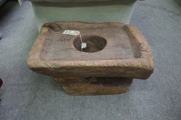 A hardwood mortar of naturalistic form, with a carved rectangular top and central circular well, 65cm wide.