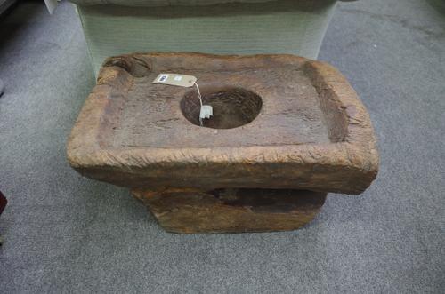 A hardwood mortar of naturalistic form, with a carved rectangular top and central circular well, 65cm wide.