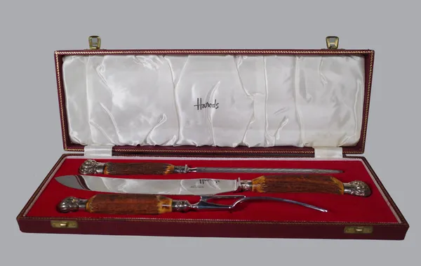 Harrods London; a three piece stag horn handled carving set, steel blades, unmarked white metal pommels and mounts, cased, 42cm wide.