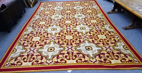 A tapestry carpet, the burgundy field with rows of large ivory roundel shaped  fleur-de-lys medallions, single plain border, 332cm x 490cm.