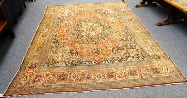 A Tabriz carpet Persian, the madder field with a dark brown and pale indigo rosette medallion, matching spandrels, floral sprays, a madder palmette an