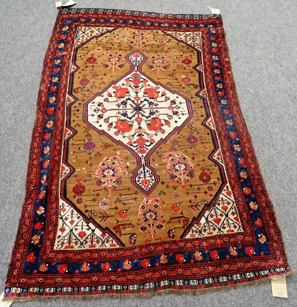 A Ghasghai rug, the brown field with an ivory diamond of flowers ivory spandrels, all with floral sprays, an indigo flower border 176cm x 106cm.