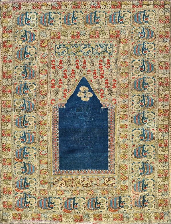 A Ghiordes prayer rug, Turkey, the plain indigo mehrab with a flower filled arch, stylised plant and leaf border, 183cm x 140cm.  Illustrated.  £20