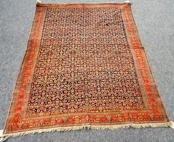 A fine Senneh rug, Persian, the dark indigo field with an allover herati design, a madder palmette and leaf spray border 186cm x 129cm.