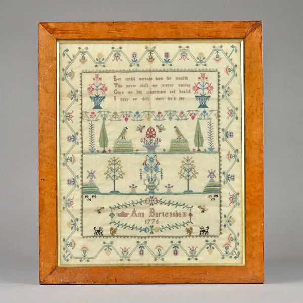 A needlework sampler by Ann Burtenshaw 1776, depicting moral verse over flora and fauna in a wide matching border and housed in a burr maple frame, (a