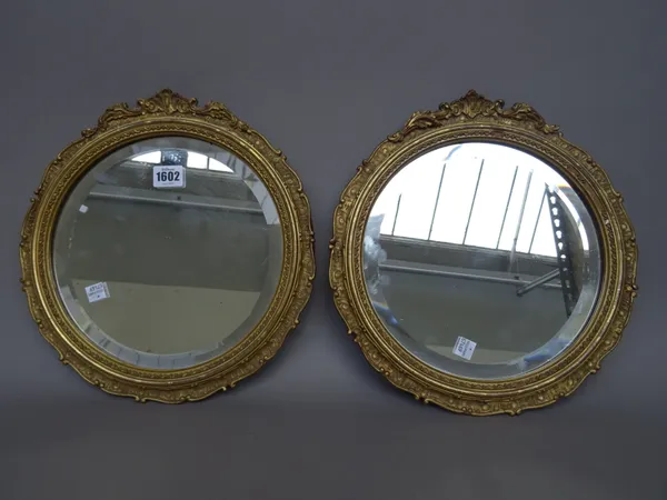 A pair of early 20th century circular mirrors, with bevelled plate and moulded frames, 33cm diameter, (2).