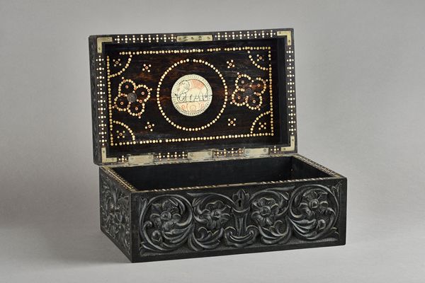 A 19th century Anglo-Indian rectangular ebony box, profusely foliate carved with bone inlaid interior, 38cm wide x 18cm high. Illustrated.