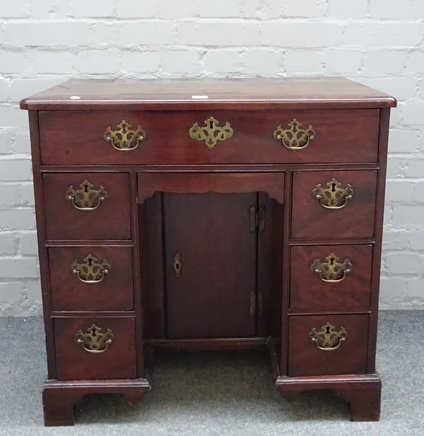 A George III mahogany kneehole writing desk with eight drawers about the kneehole cupboard on bracket feet, 76cm wide x 74cm high.