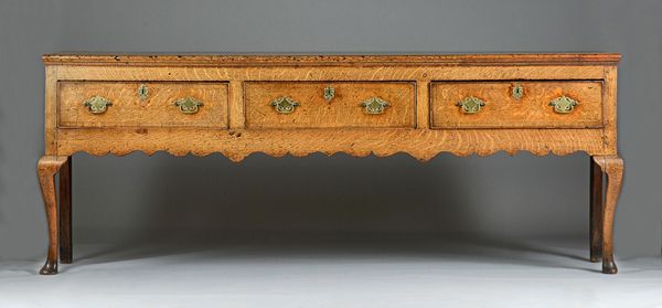 A mid-18th century oak dresser base, the shaped frieze with three drawers on cabriole supports, 214cm wide x 82cm high. Illustrated.