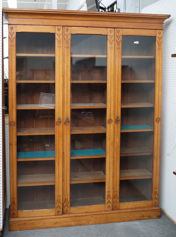 A Victorian Aesthetic movement honey oak floor standing display cabinet with three full length glazed doors, 175cm wide x 225cm high.