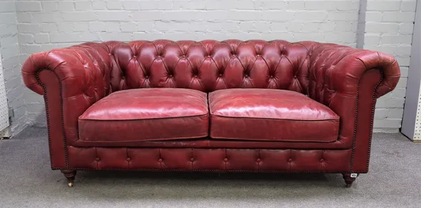 A 20th century brass studded red leather upholstered button back Chesterfield on turned supports, 180cm wide x 74cm high.