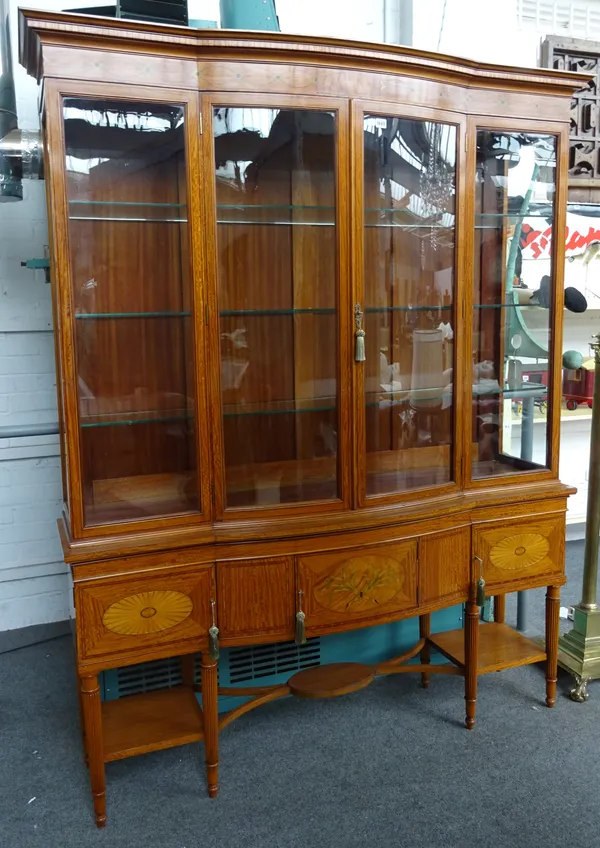 An Edwardian inlaid satinwood break bowfront display cabinet/cupboard, with a pair of glazed doors, over three cupboards, on reeded supports, united b