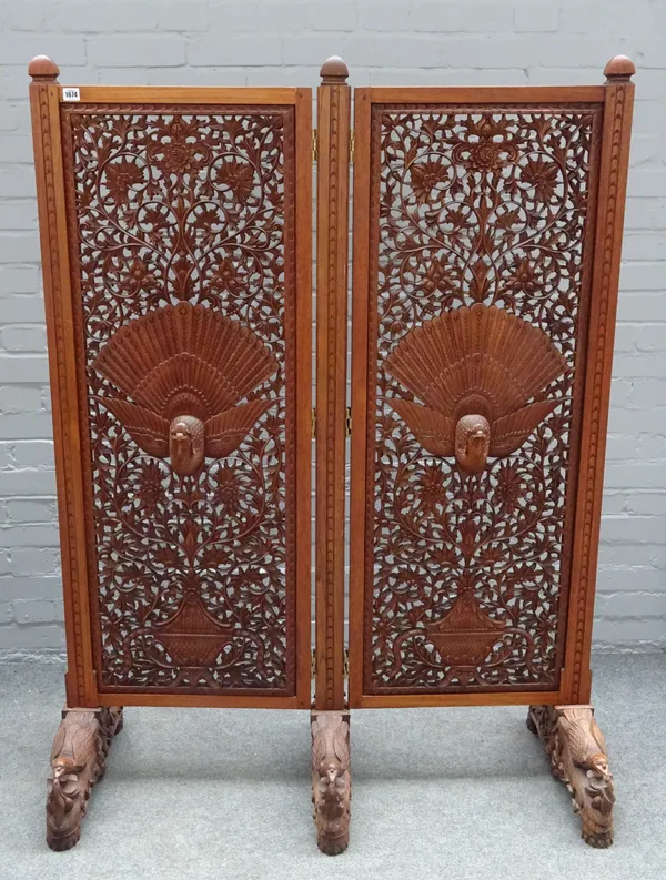 An early 20th century Burmese carved and pierced hardwood two fold screen, on exotic bird feet, 115cm wide x 154cm high