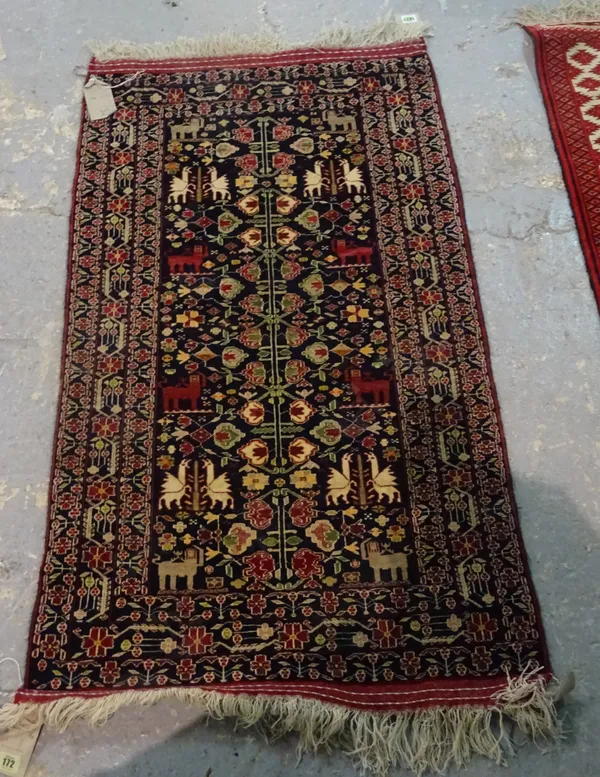 A Beluchistan rug, the field decorated with a stylised flowering plant, pairs of winged horses and pairs of lions, complementary flower border, 126cm