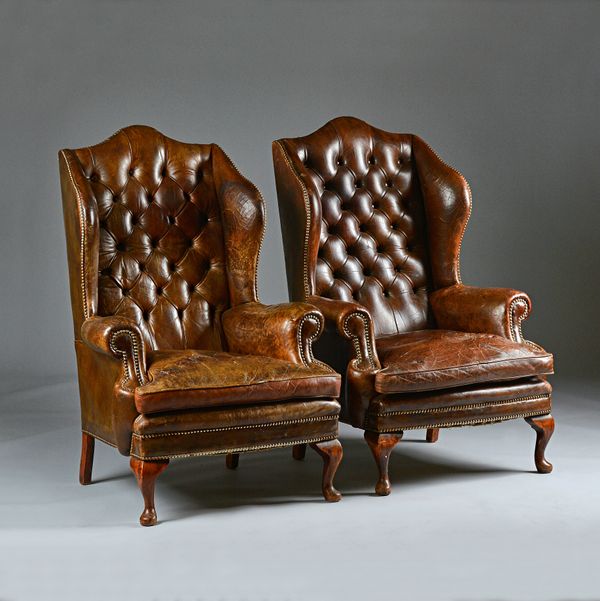 A pair of George I style brass studded brown leather upholstered wingback armchairs on cabriole supports, 80cm wide x 117cm high (2). Illustrated.