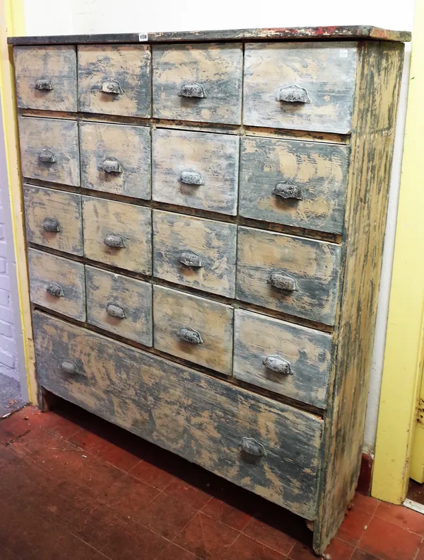 A distressed painted pine bank of four rows of four short drawers over one long drawer, 128cm wide x 149cm high.