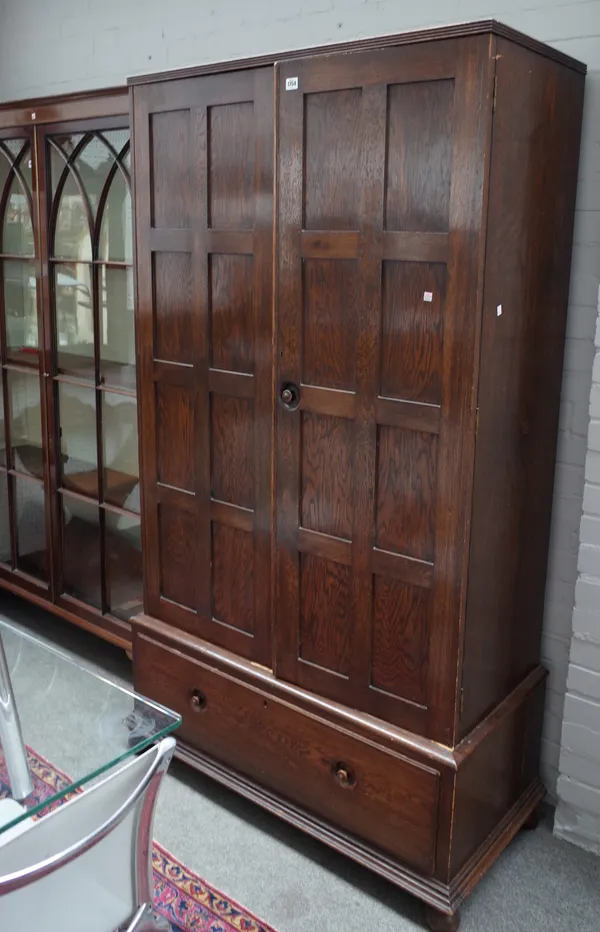 An Arts & Crafts oak wardrobe, with pair of doors over one long drawer, all with recessed turned handles, 108cm wide x 197cm high.