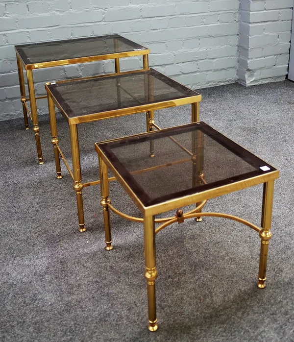 A nest of three 20th century lacquered brass and smoked glass occasional tables on reeded supports, the largest 56cm wide x 46cm high.