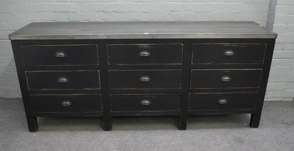 A zinc topped side cabinet, the ebonised base with three rows of three drawers, 182cm wide x 77cm high.