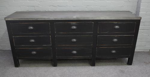 A zinc topped side cabinet, the ebonised base with three rows of three drawers, 182cm wide x 77cm high.