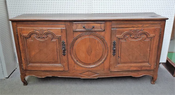 An early 19th century French oak dresser base with pair of carved arch panel doors on squat cabriole supports, 193cm wide x 94cm high.