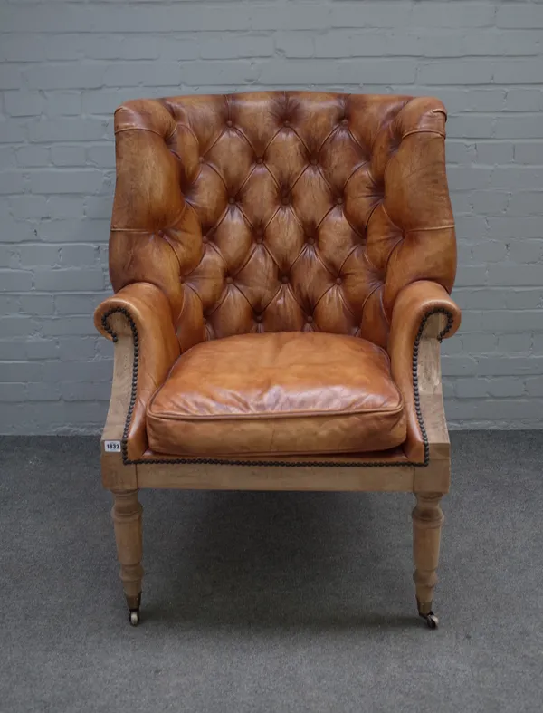 A brown leather upholstered high tub back armchair on bleached mahogany turned supports, 78cm wide x 110cm high.