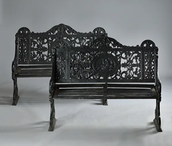 A pair of 20th century black painted cast iron garden benches, relief cast with a scantily clad lady, 123cm wide x 98cm high (2). Illustrated.