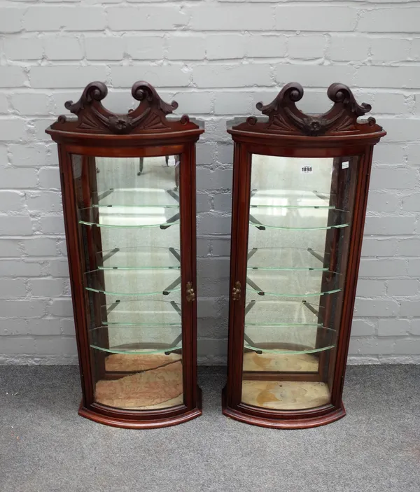 A pair of Victorian mahogany framed bowfront hanging display cabinets, with scroll carved crest, 41cm wide x 105cm high (2).