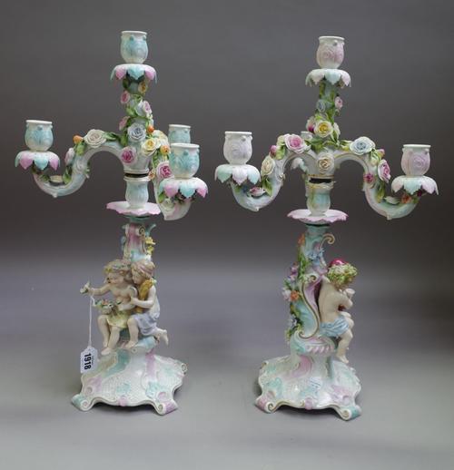 A pair of Sitzendorf four-light candelabra, circa 1900, each modelled with two putti representing a season, seated against a column beneath three scro