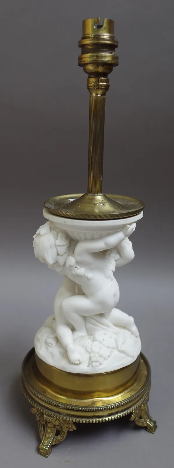 A parian table lamp with gilt-metal mounts, late 19th century, modelled as two kneeling putti amongst fruiting vine and corn sheaves, overall height 3