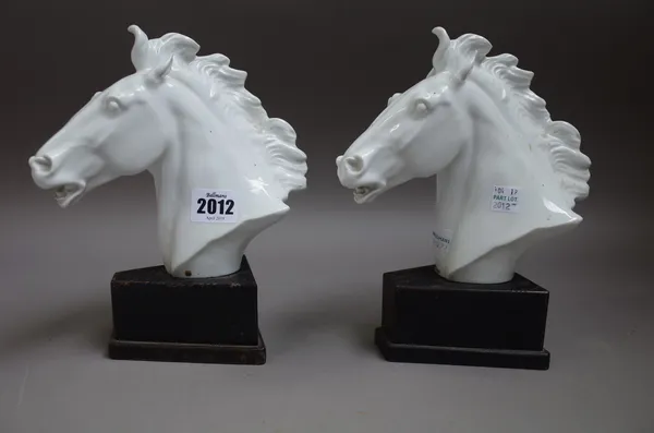 Two Meissen white glazed porcelain horse head busts, each signed 'ERICH OEHME 1949', cancelled blue crossed swords mark, raised on an ebonised wooden