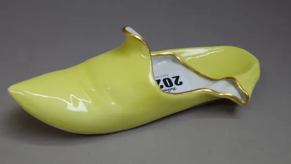 A Meissen model of a yellow slipper, late 19th, with gilt rims and puce edged heel. blue crossed swords mark, 16.5cm. length.