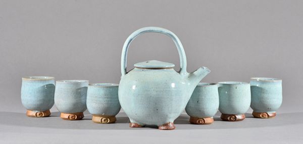 Clare Sutcliffe (1943-2019), a tea pot and six beakers, shino glaze and wood fired, makers mark, (7), 9cm high. Illustrated.