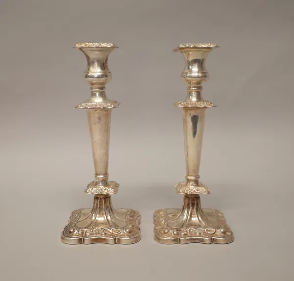 A pair of silver table candlesticks, each of shaped squared form, having tapering stems, raised on a shaped square base, Sheffield 1964 (loaded), heig