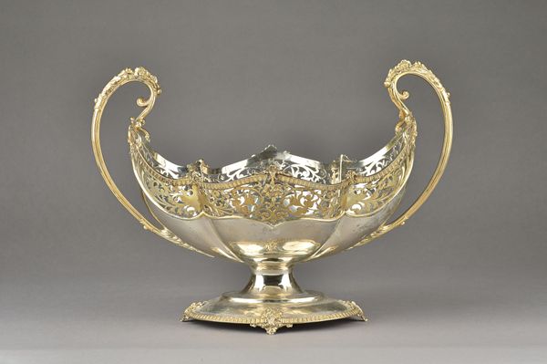 A large parcel gilt twin handled centrepiece bowl, of shaped oval form, decorated with a wide pierced band, between split handles and raised on a deco