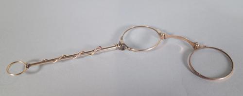 A pair of early 20th century gold coloured folding lorgnettes, shaft with encircling snake motif with red glass eyes, apparently unmarked, 14cm long.