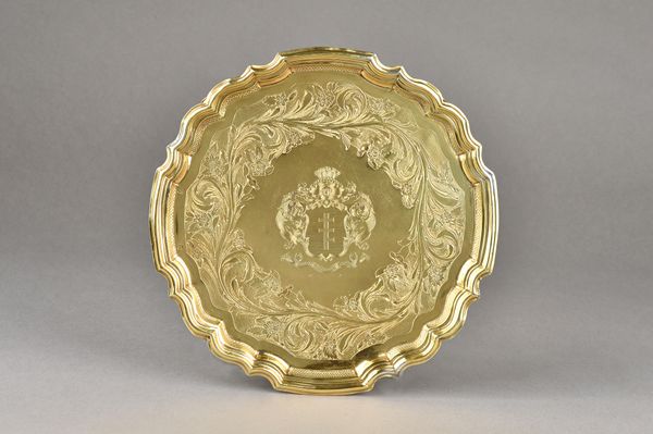 A German silver gilt salver, of shaped circular form, with a pie-crust rim, engraved to the centre with a coat of arms and a motto, within a floral an