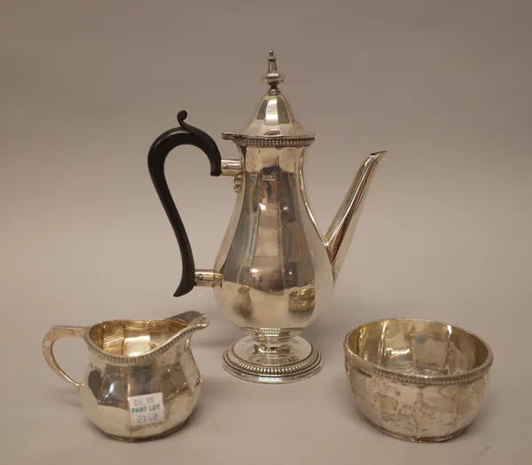 A silver three piece coffee set, comprising; a coffee pot, a sugar bowl and a milk jug, each piece of panelled form below gadrooned rims, the coffee p