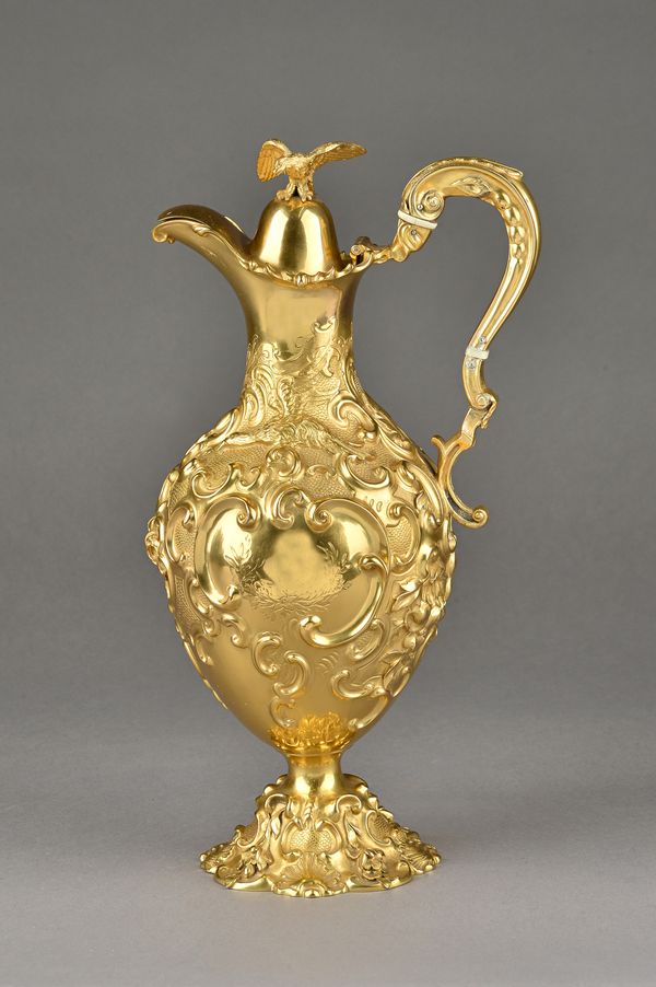 A Victorian silver gilt claret jug, embossed and chased with scrolls, flowers and birds, the hinged lid with a bird of prey finial, height 34cm, Londo