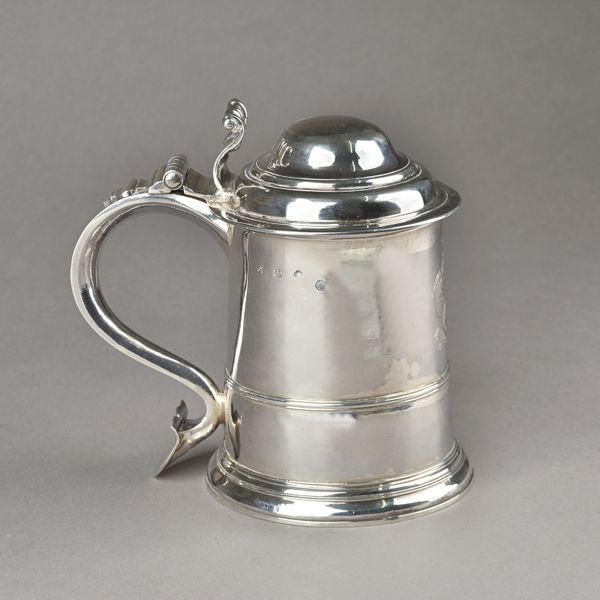 A George II silver tankard, of tapered cylindrical form, later engraved with a coat of arms, a crest and a motto, the scrolled handle with a shield sh