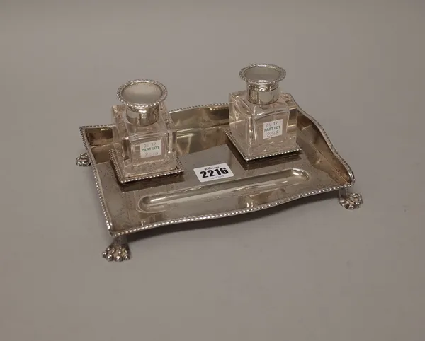 A silver rectangular twin bottle inkstand, the stand decorated with gadrooned rims and raised on four paw feet, with a pair of silver hinge lidded squ