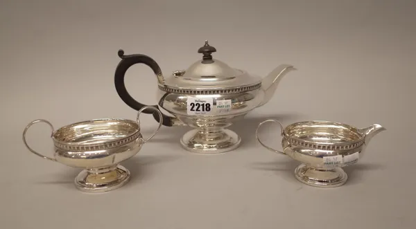 A silver three piece tea set, comprising; a teapot, a twin handled sugar bowl and a milk jug, each piece having a decorated border, the teapot with bl